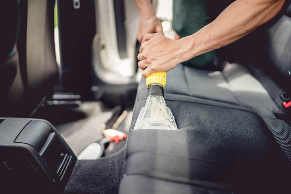an image of a car detailing Ballarat cleaner using a wet vacuum to clean the backseat of a car